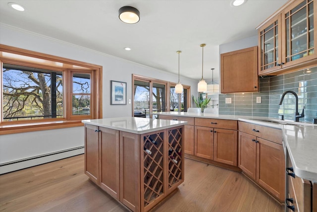 kitchen with tasteful backsplash, a sink, light wood-style floors, a peninsula, and brown cabinetry