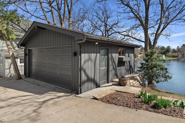 detached garage with driveway and a water view