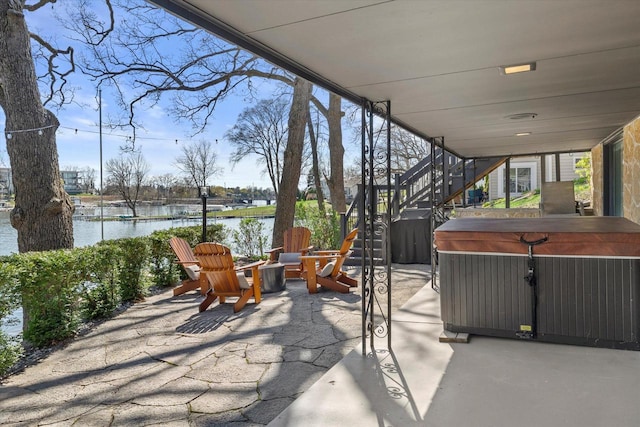 view of patio / terrace featuring stairs, a water view, and a hot tub