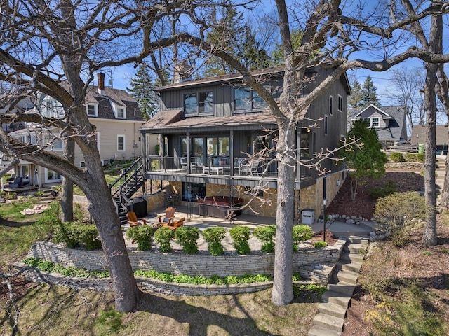 rear view of house with a patio area, a hot tub, and stairs