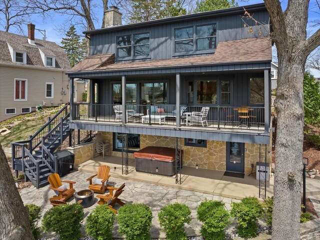 back of house with a balcony, stone siding, a fire pit, and a patio area