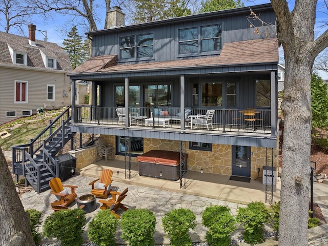 back of house with a balcony, stone siding, a fire pit, and a patio area