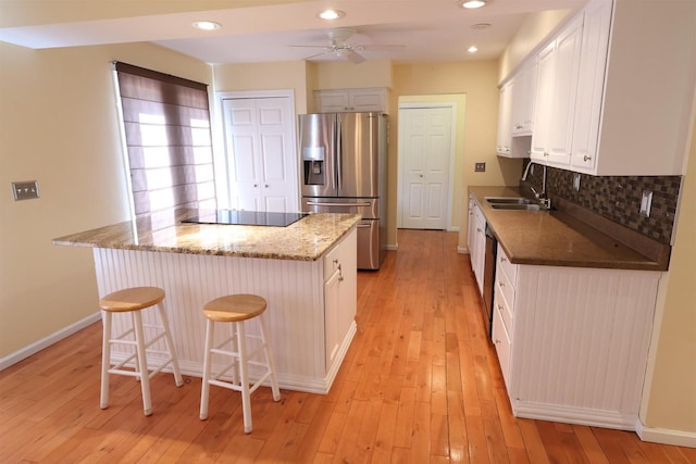 kitchen featuring a sink, black electric cooktop, ceiling fan, a center island, and stainless steel fridge with ice dispenser