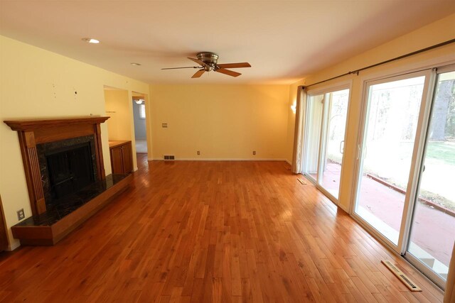 unfurnished living room with visible vents, ceiling fan, light wood-style flooring, and a premium fireplace
