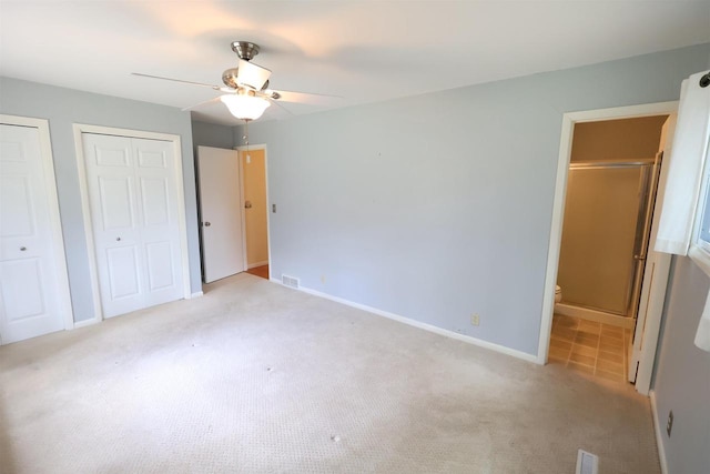 unfurnished bedroom featuring visible vents, multiple closets, ensuite bath, and carpet floors