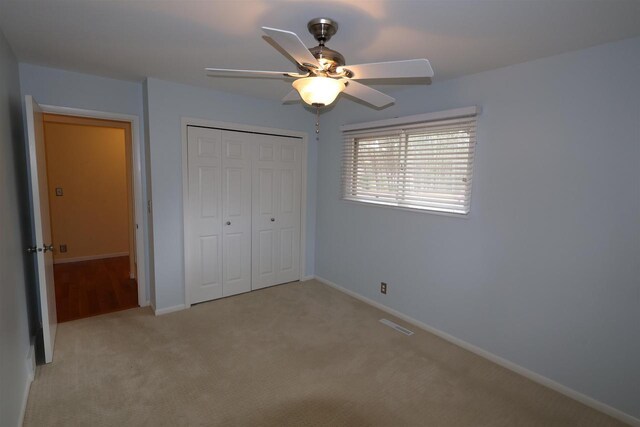 unfurnished bedroom with a closet, ceiling fan, visible vents, baseboards, and light colored carpet