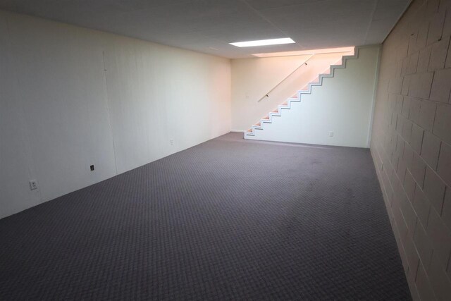 finished basement with concrete block wall, stairs, and carpet