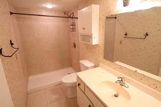full bath featuring vanity, a tile shower, toilet, and tile patterned flooring