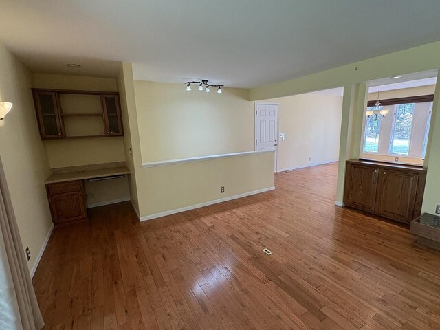 interior space featuring baseboards, wood finished floors, and an inviting chandelier