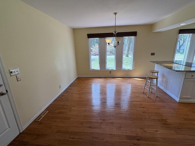 unfurnished dining area featuring dark wood finished floors, an inviting chandelier, and plenty of natural light