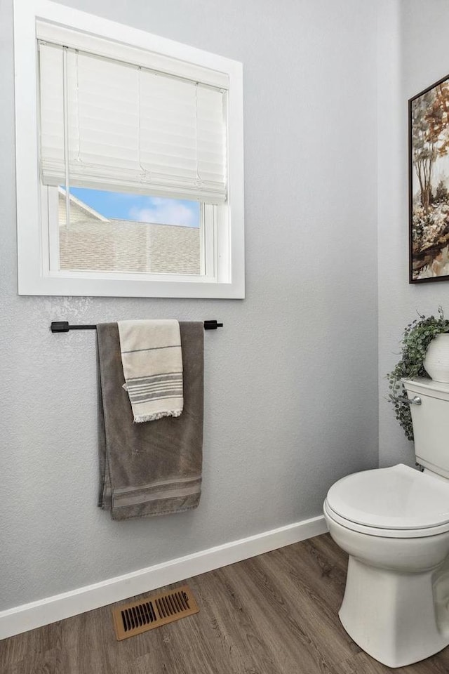 bathroom with toilet, visible vents, wood finished floors, and baseboards