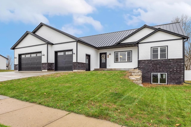modern inspired farmhouse featuring a front yard, metal roof, driveway, stone siding, and an attached garage