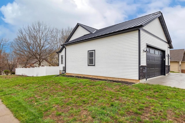 view of home's exterior with a standing seam roof, metal roof, a lawn, an attached garage, and fence