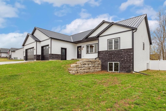 modern farmhouse style home with a standing seam roof, fence, stone siding, and a garage