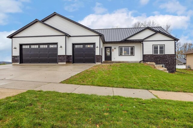 modern farmhouse with a front yard, a garage, metal roof, stone siding, and concrete driveway