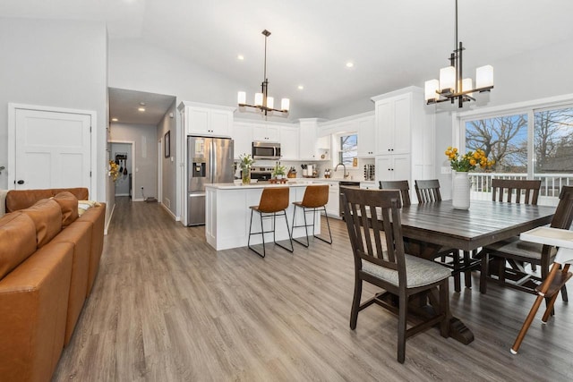 dining area featuring high vaulted ceiling, an inviting chandelier, and light wood-style flooring