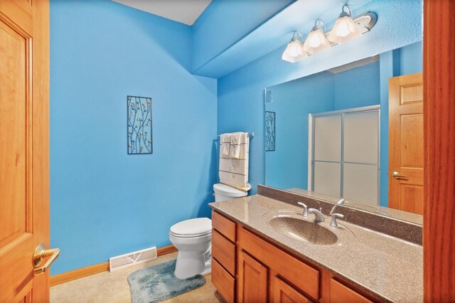 bathroom with visible vents, a shower with door, baseboards, toilet, and vanity