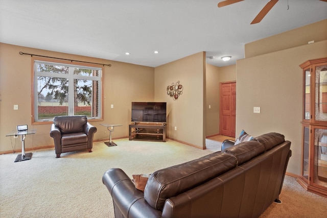 living area with baseboards, light carpet, and ceiling fan