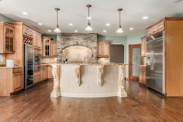 kitchen with built in appliances, arched walkways, glass insert cabinets, and dark wood-style floors