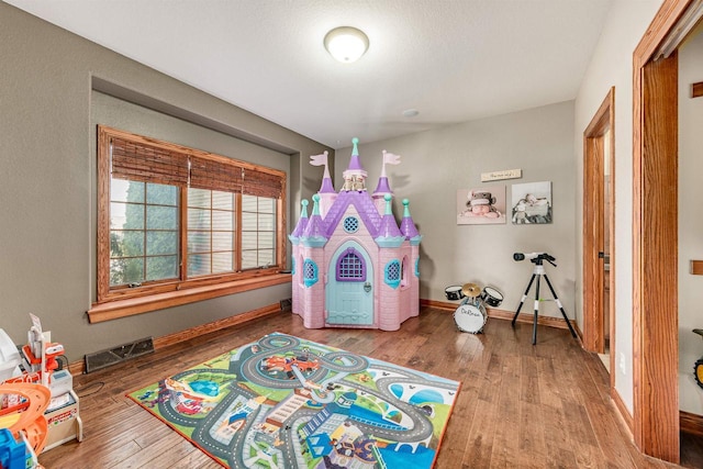 game room featuring wood finished floors, visible vents, and baseboards