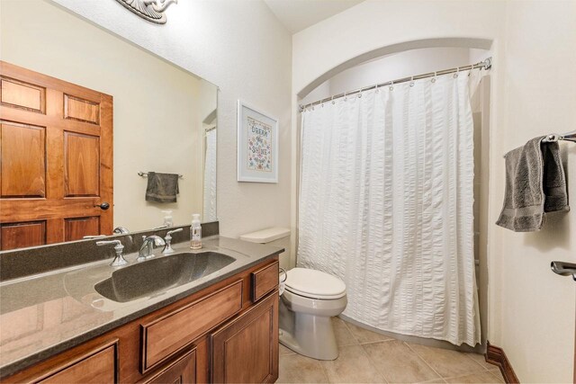 bathroom with tile patterned floors, a shower with shower curtain, toilet, and vanity