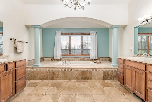 full bath featuring a chandelier, decorative columns, a bath, and a sink