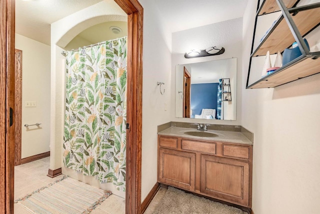 full bathroom with a shower with curtain, tile patterned flooring, vanity, and baseboards