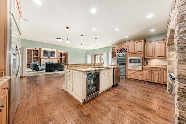 kitchen featuring a sink, wine cooler, a warming drawer, appliances with stainless steel finishes, and open floor plan