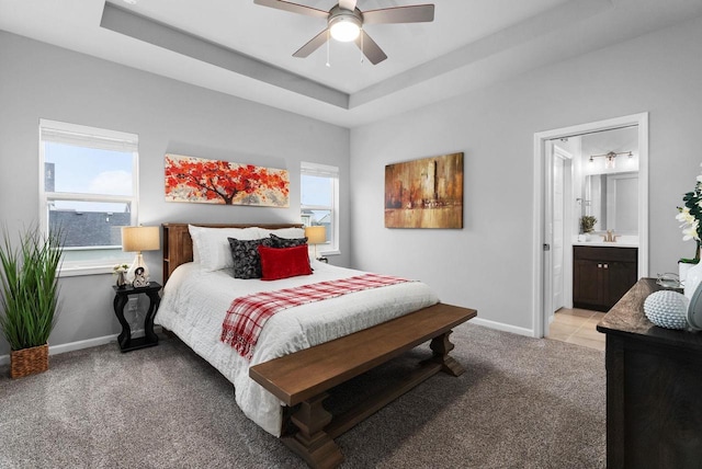 bedroom featuring baseboards, a ceiling fan, ensuite bathroom, and light carpet