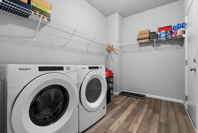clothes washing area with baseboards, laundry area, independent washer and dryer, and wood finished floors