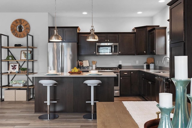 kitchen with dark brown cabinets, a sink, light countertops, a center island, and stainless steel appliances