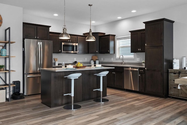 kitchen with a sink, light countertops, stainless steel appliances, and wood finished floors