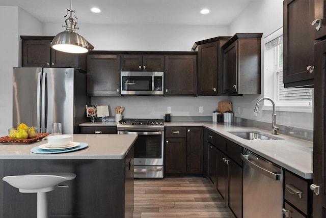 kitchen with dark brown cabinets, dark wood-style floors, light countertops, a sink, and stainless steel appliances