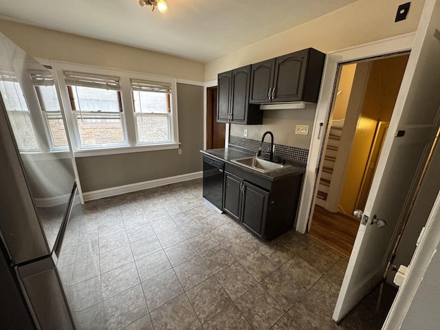 kitchen with dark countertops, dishwasher, a sink, and baseboards