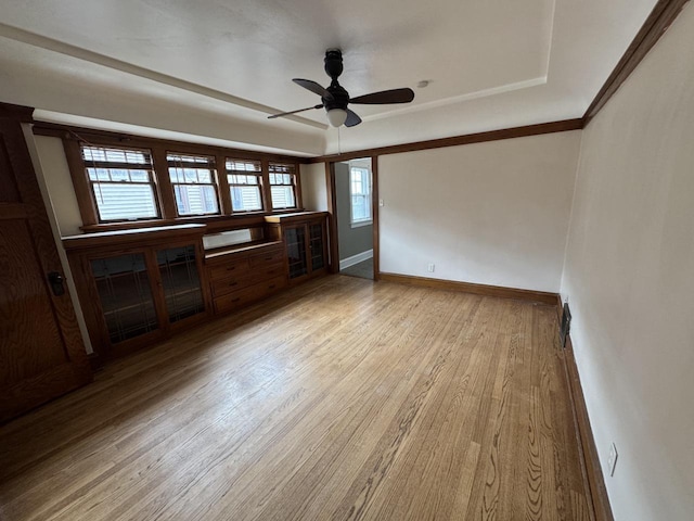 unfurnished living room with baseboards, a raised ceiling, ceiling fan, and wood finished floors