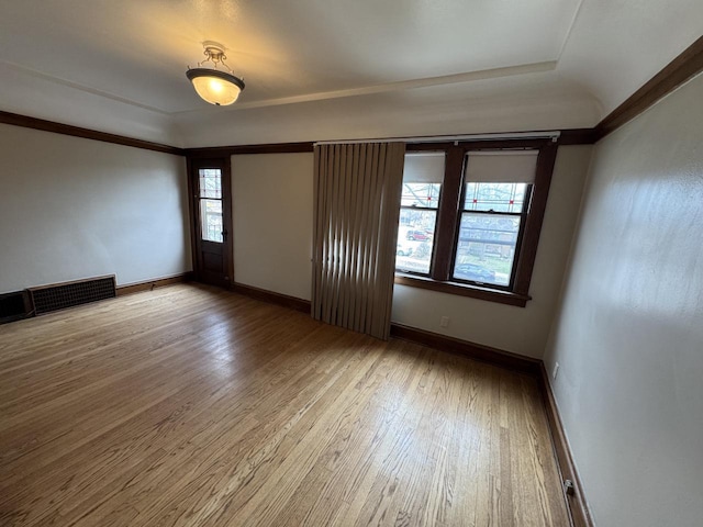 unfurnished room with wood finished floors, a tray ceiling, visible vents, and baseboards