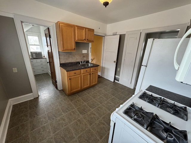 kitchen featuring brown cabinets, tasteful backsplash, a sink, dark countertops, and white appliances