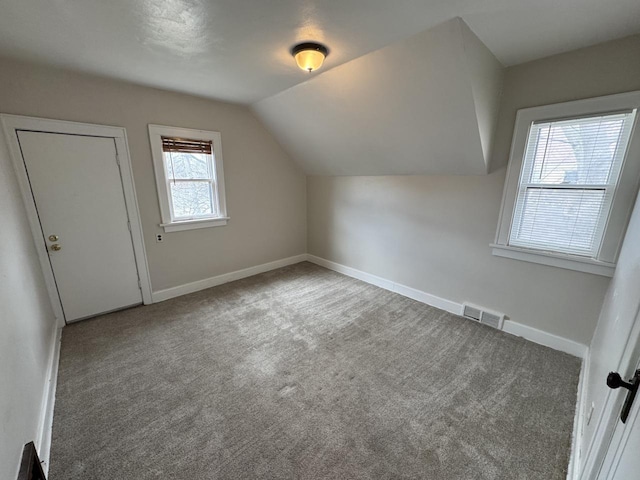 additional living space with lofted ceiling, visible vents, baseboards, and carpet floors