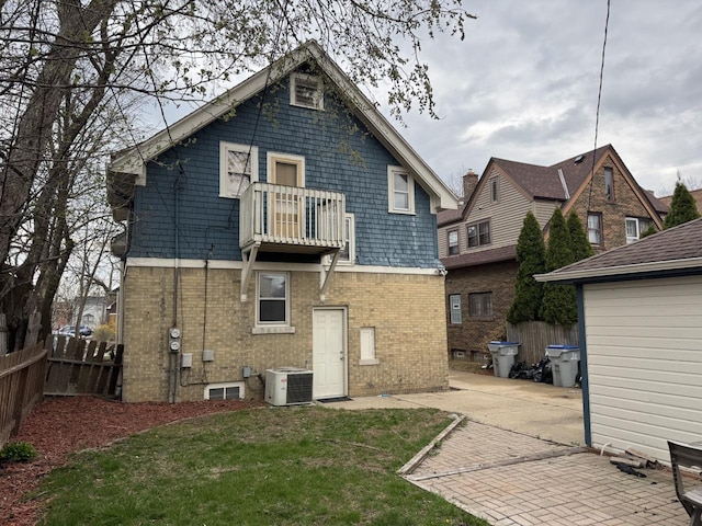 rear view of property featuring a patio, central air condition unit, a balcony, brick siding, and fence