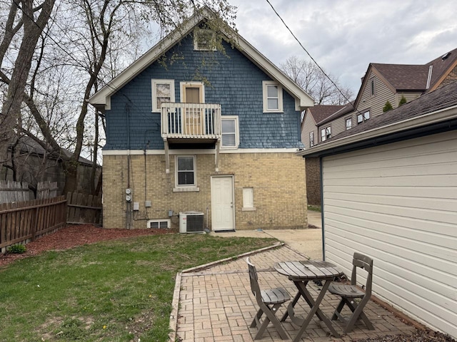 rear view of property with a yard, brick siding, fence, central air condition unit, and a balcony