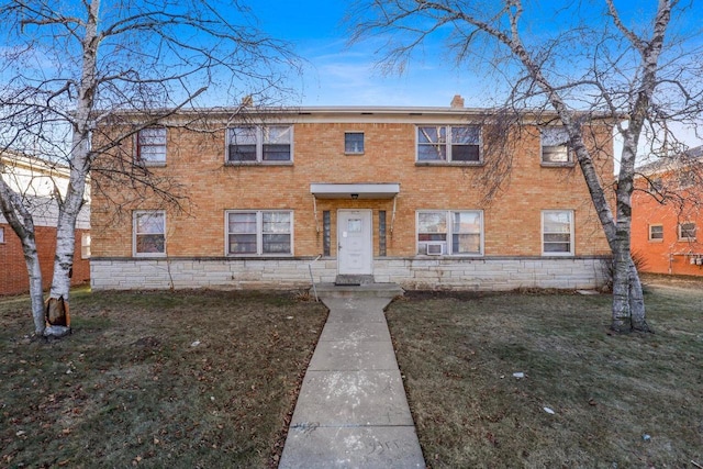 view of front of property featuring a chimney, brick siding, and a front yard