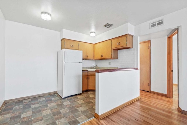 kitchen with visible vents, light countertops, freestanding refrigerator, and baseboards
