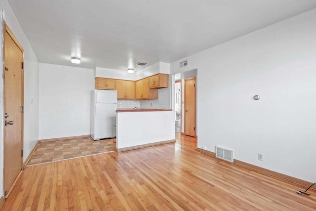 kitchen with visible vents, light countertops, light wood finished floors, and freestanding refrigerator
