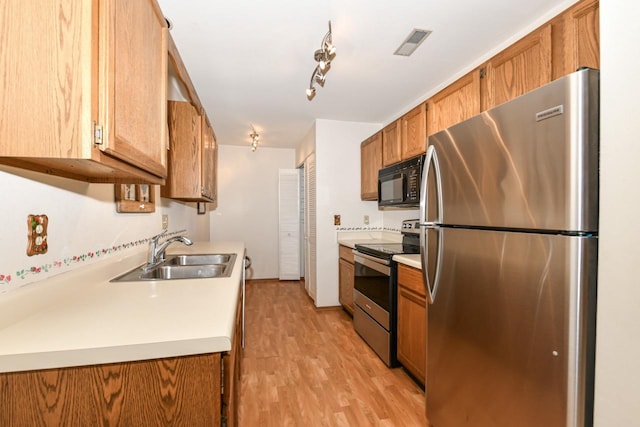 kitchen with a sink, appliances with stainless steel finishes, visible vents, light countertops, and brown cabinetry