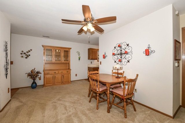dining room featuring a ceiling fan, baseboards, and light carpet