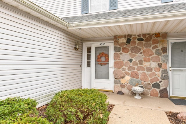 entrance to property with roof with shingles and stone siding