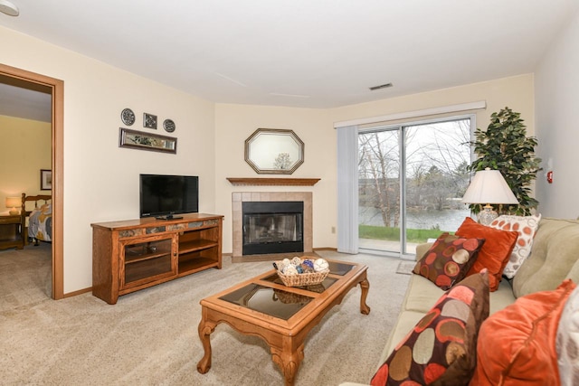 carpeted living room with a tile fireplace, visible vents, and baseboards
