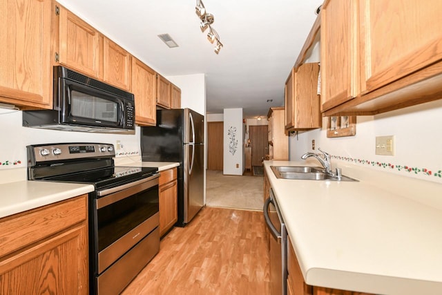 kitchen with stainless steel appliances, light countertops, light wood finished floors, a sink, and visible vents