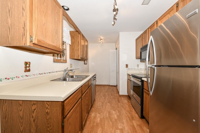 kitchen featuring a sink, brown cabinetry, light wood-style flooring, light countertops, and appliances with stainless steel finishes