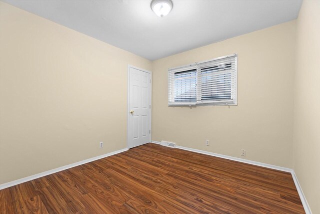9073 N Joyce Ave, Milwaukee, WI 53224 - empty room with baseboards, visible vents, and dark wood-type flooring